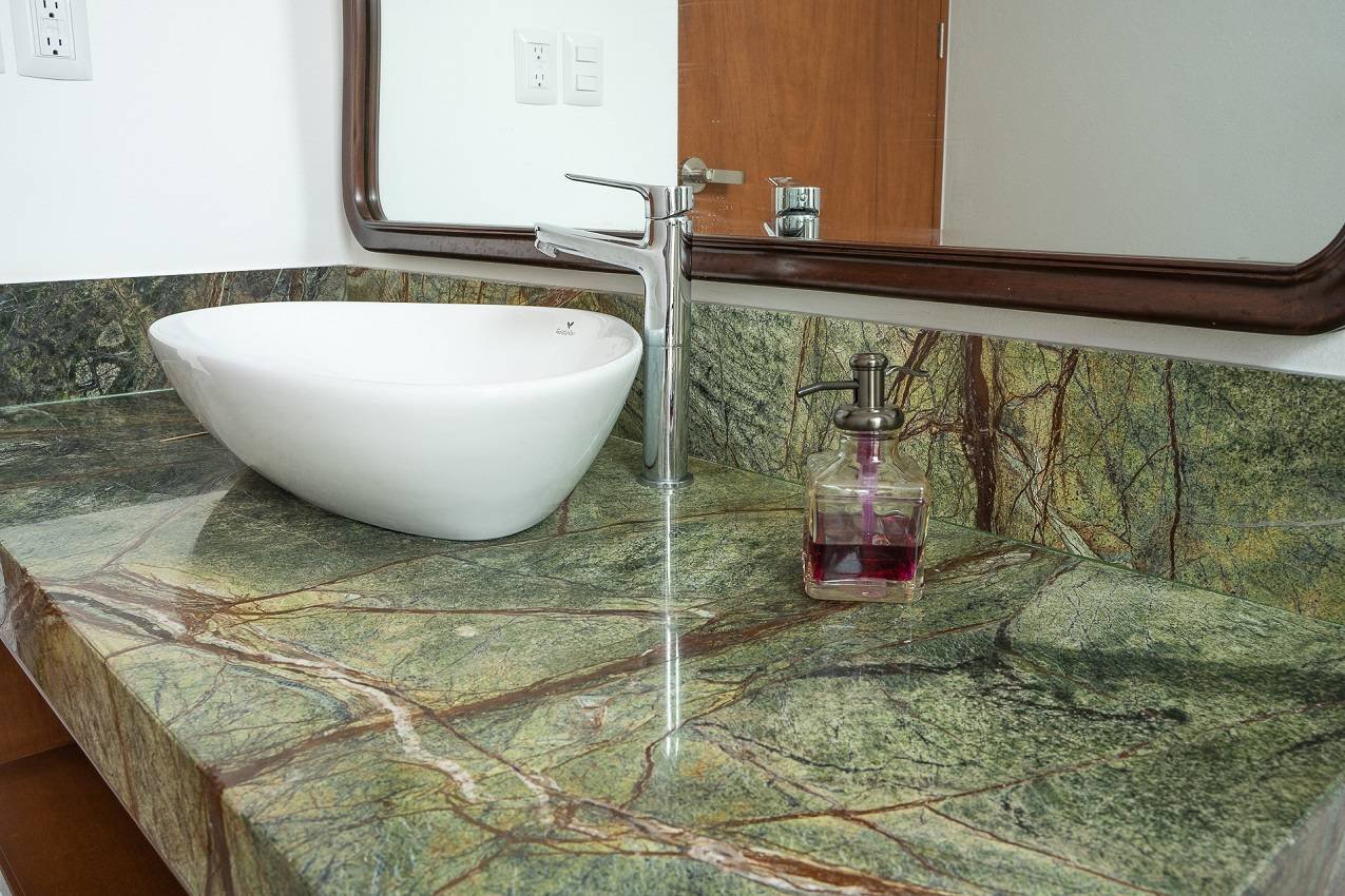 Green Onyx marble countertop with white vessel sink and wall-mounted mirror in a modern bathroom vanity setup.