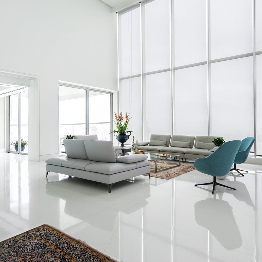Modern living room with floor-to-ceiling windows and glossy white marble flooring, featuring minimalist furniture and a bright, airy ambiance.