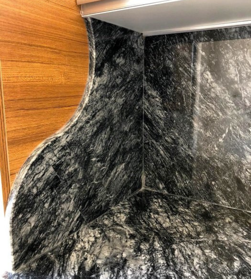 Close-up of Black Pearl marble countertop and backsplash – dynamic dark tones and textured veining by Natural Stone Spain.