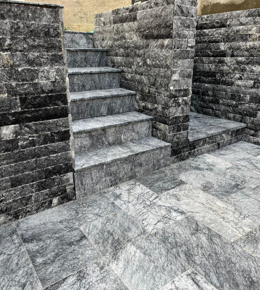 Outdoor stairs and walls crafted from textured Black Pearl marble – durable and stylish natural stone by Natural Stone Spain