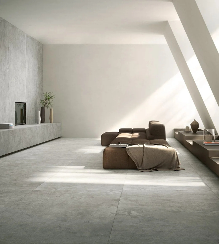 Minimalist living room with natural light highlighting Blue Bateig eMarble flooring, paired with low-profile brown sofas and clean architectural lines.