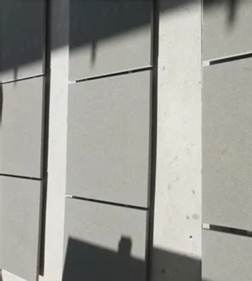 Exterior wall facade clad in Blue Bateige Marble panels, showcasing clean lines and a modern architectural finish with natural shadow play.