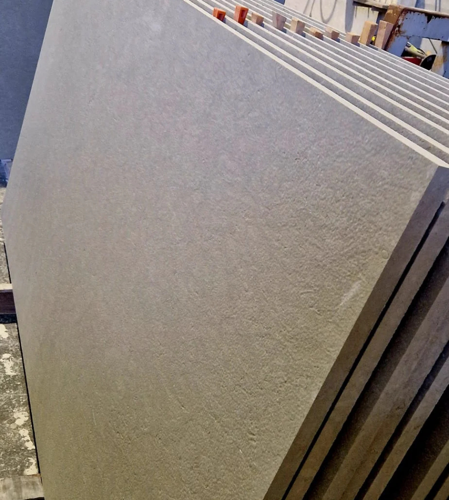 Stacked slabs of Blue Bateige Marble in a stone warehouse, displaying fine-grain texture and consistent grey tone ideal for modern construction.