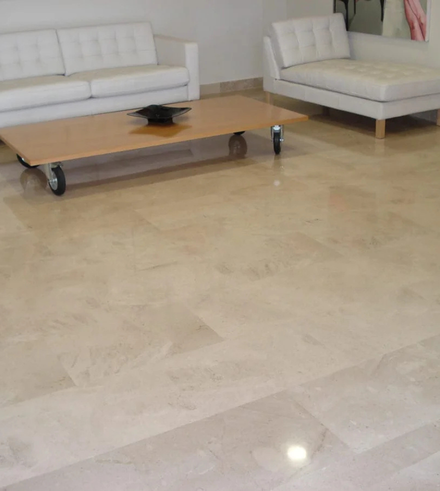 Modern living room with white sofas and a light beige polished marble floor, showcasing the elegant and glossy finish of Crema Levante Marble.