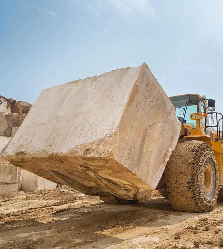 Heavy machinery lifting a large Crema Valencia Marble block at a Spanish quarry – premium raw stone extraction by Natural Stone Spain.