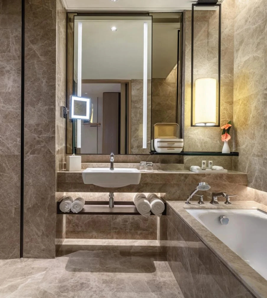 Luxurious bathroom interior featuring Light Emperador marble on walls, flooring, and bathtub surround, creating a warm and elegant ambiance.