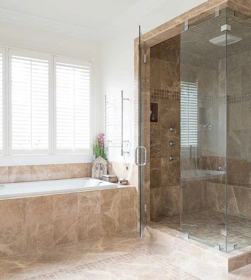 Elegant bathroom showcasing Light Emperador Marble in warm brown tones, used for the bathtub surround and shower walls, adding luxury and richness to the space.