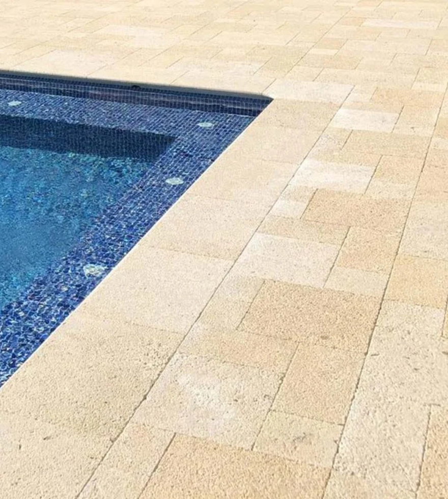 Poolside deck with non-slip beige limestone tiles – elegant and durable outdoor stone by Natural Stone Spain.
