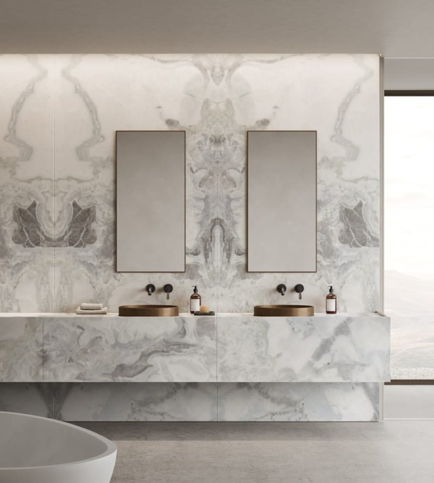 Modern luxury bathroom featuring a floating vanity and wall cladding in bookmatched White Dover Marble, complemented by dual mirrors, ambient lighting, and minimalist fixtures.