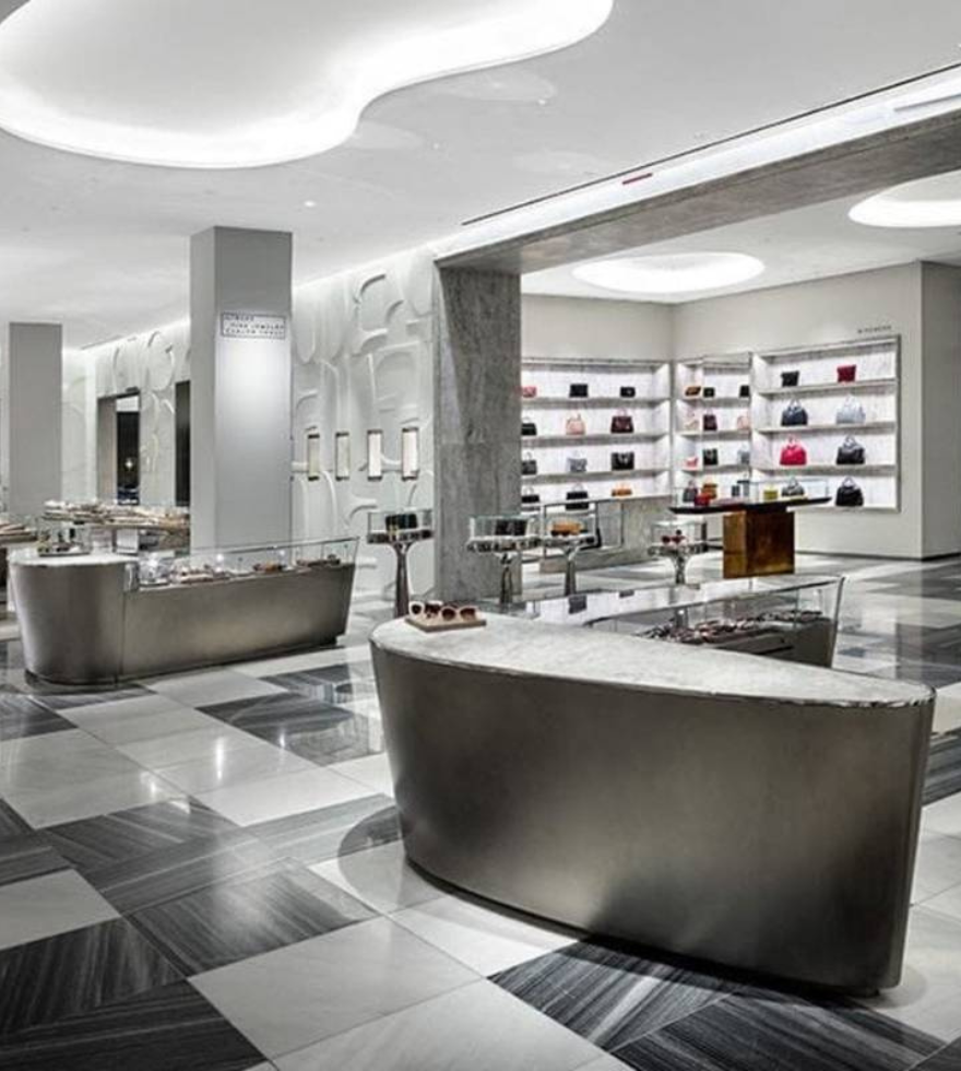 High-end retail store interior featuring a striking black and white marble floor design, sleek modern furniture, and illuminated shelving displaying luxury handbags.