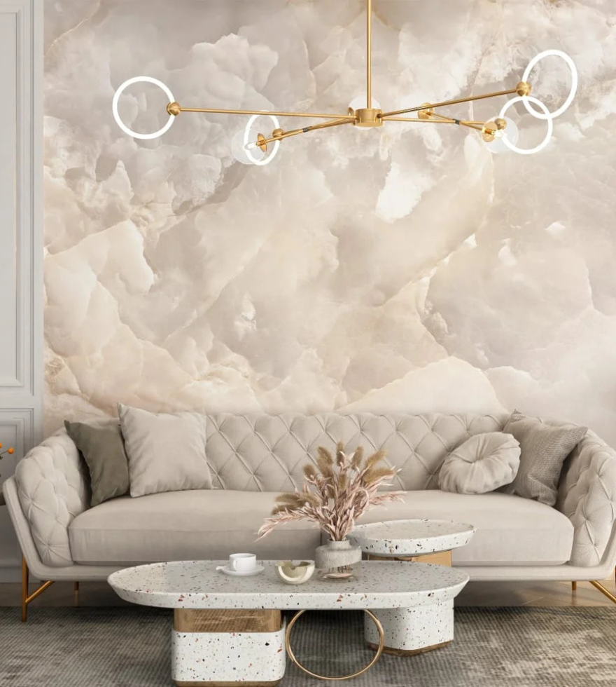 Stylish living room with a statement wall clad in soft-toned White Onyx marble, complemented by a neutral sofa, modern chandelier, and marble coffee table.