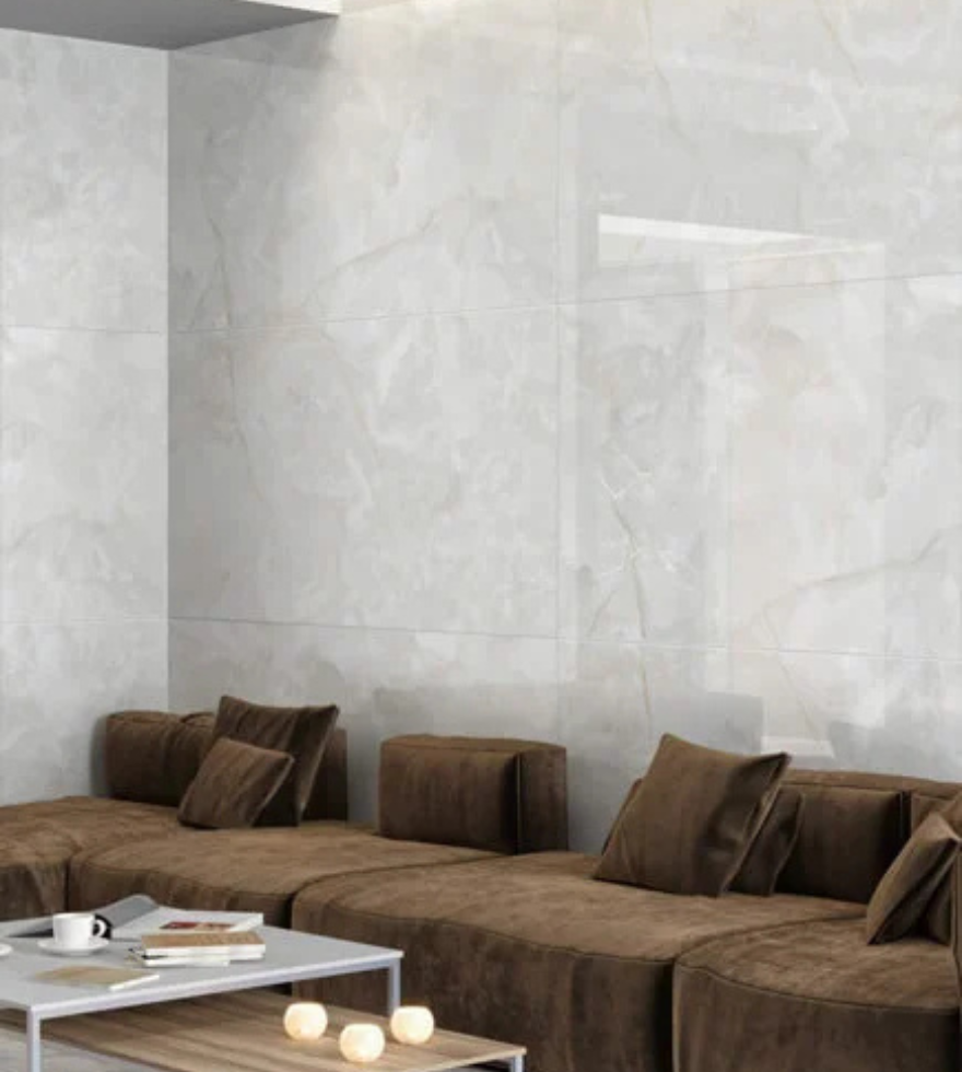 Contemporary living room featuring a wall clad in White Onyx marble with subtle veining, complemented by a sleek brown sectional sofa and a modern coffee table.